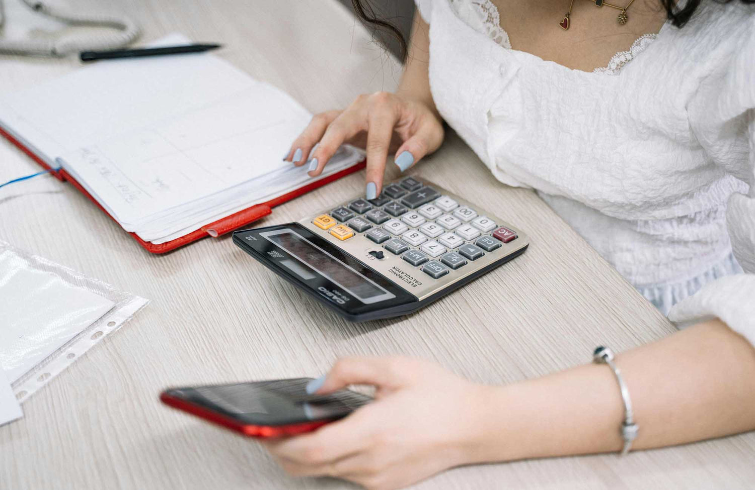 Lady in white dress using calculator and iPhone to work out wedding budget