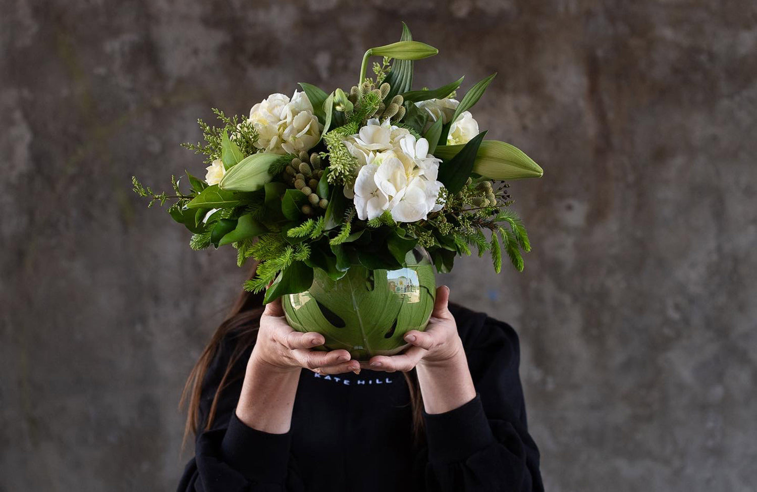 Lady in black holding a Christmas flower delivery arrangement in a glass vase