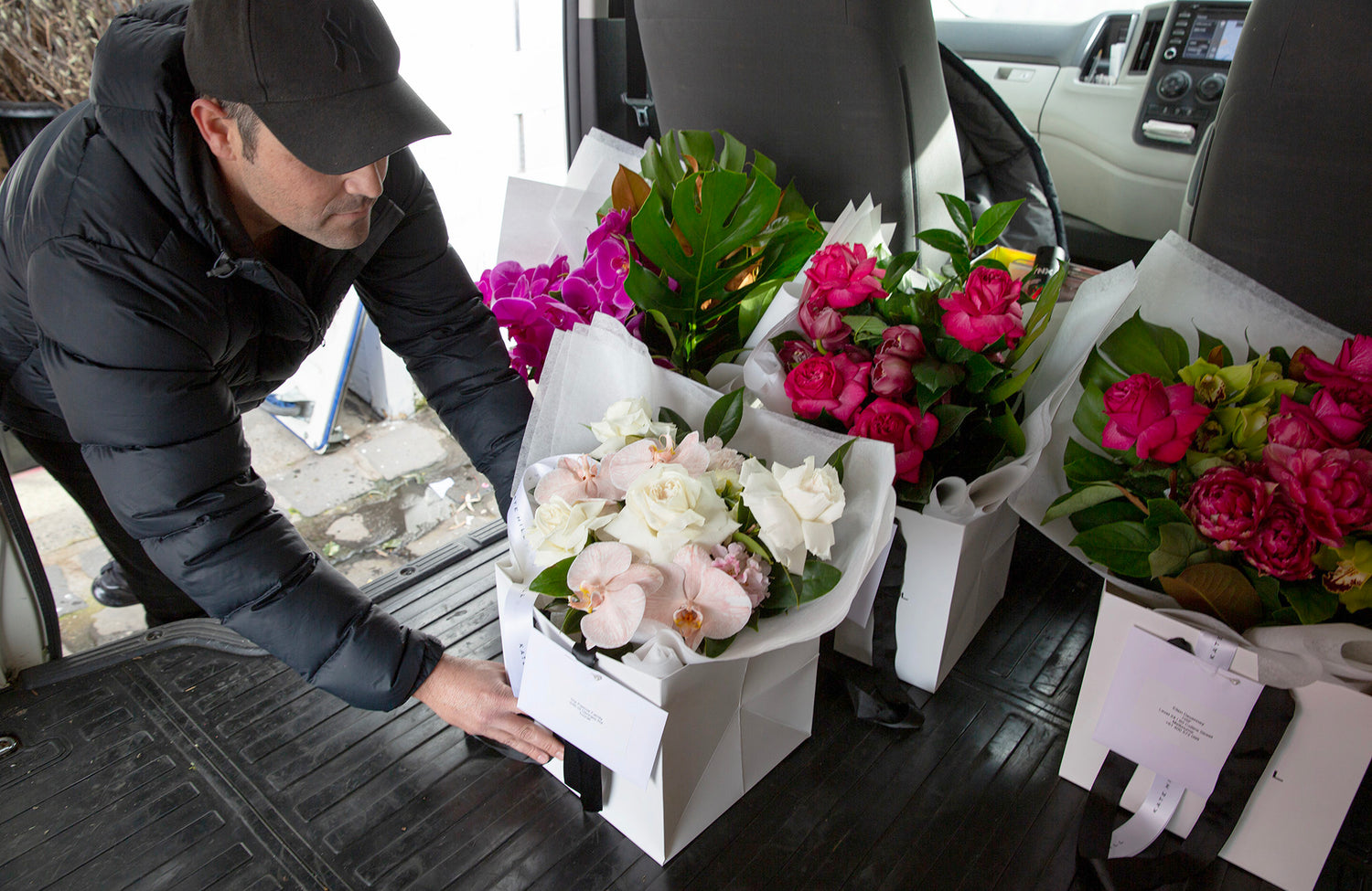 Flower delivery driver loading flower arrangements into back of a delivery van