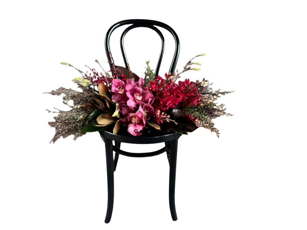 A black bentwood chair with the GARNET rich red tablescape sitting on chair, against a white wall.