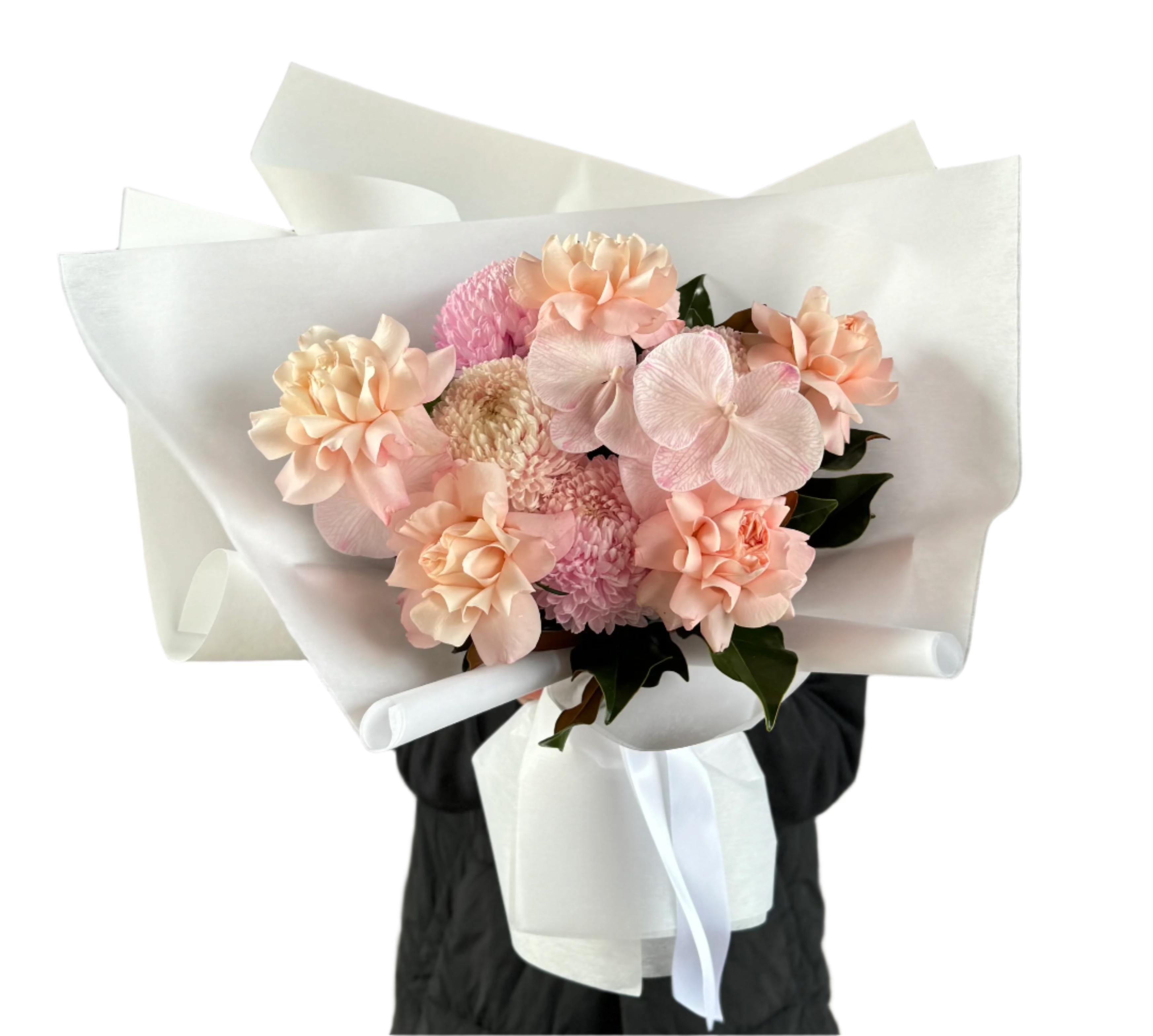 A close up of a blush pink flower bouquet, beautifully wrapped in white signature paper. Florist holding the bouquet in front of a white wall.