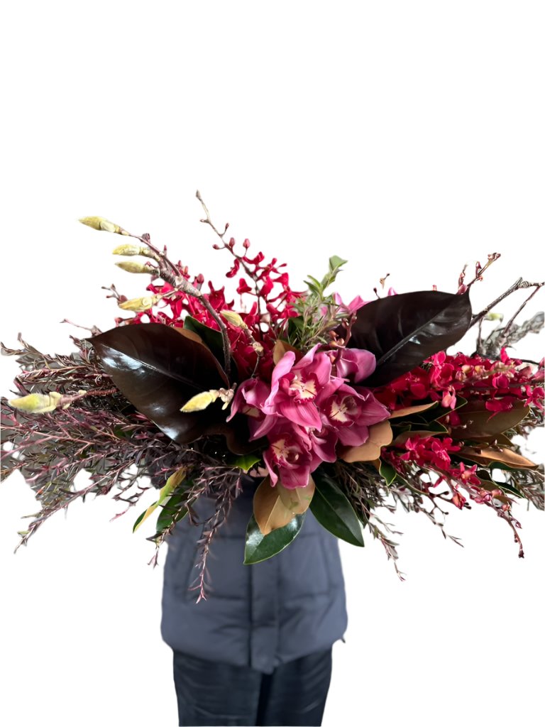 Florist holding the GARNET rich red tablescape against a white wall.