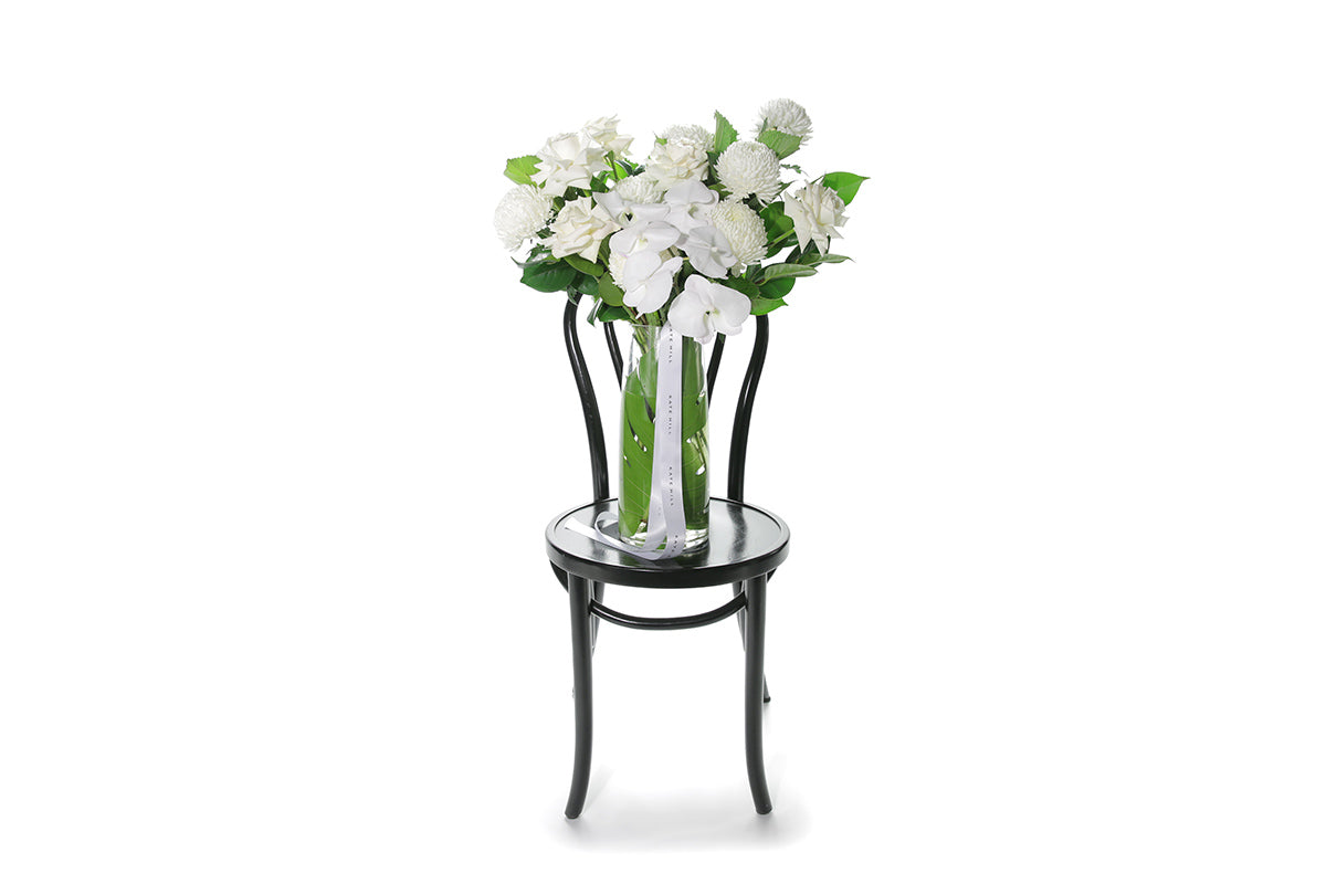 Kate Hill Flowers – large white and green birthday vase with roses, chrysanthemums and orchids in a monstera-lined tapered glass.