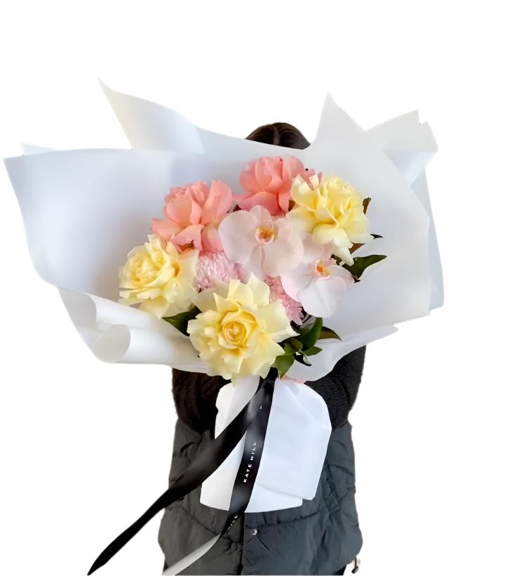 Video of florist holding a blush and lemon pastel gift bouquet in front of a white wall.