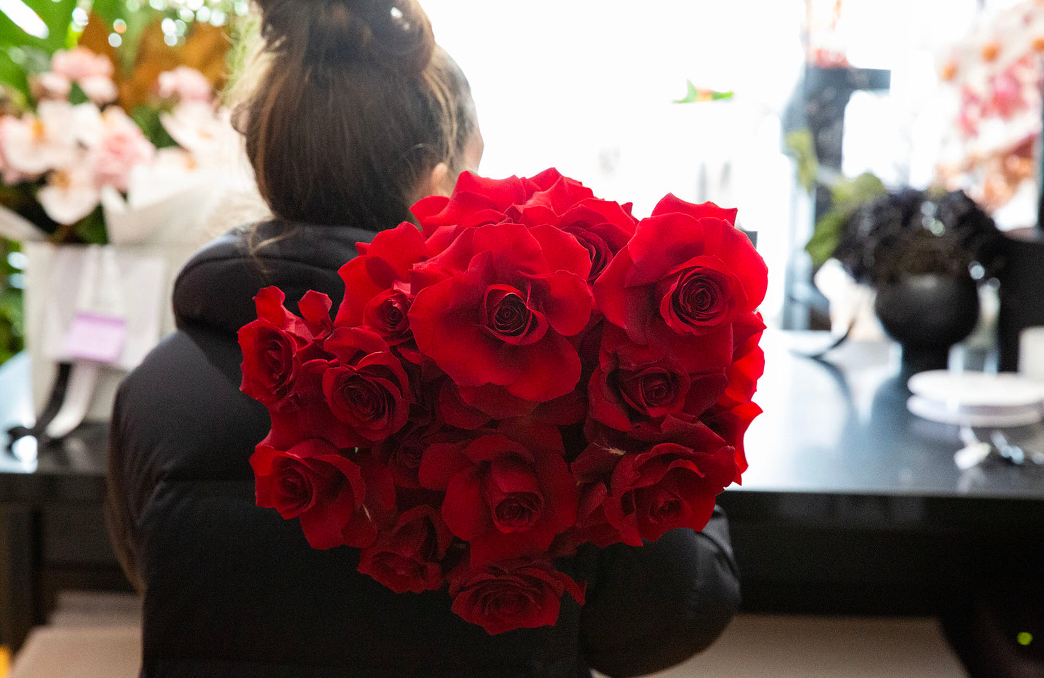 Florist in Bentleigh holding a bunch of red roses. The image is shot from behind the florist.