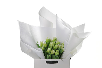 Close up image of the white double tulip bouquet. Kate Hill flower bag sitting on a black bentwood chair, displaying fresh premium white double tulip bouquet. Bouquet of 20 stems of white double tulips in image.