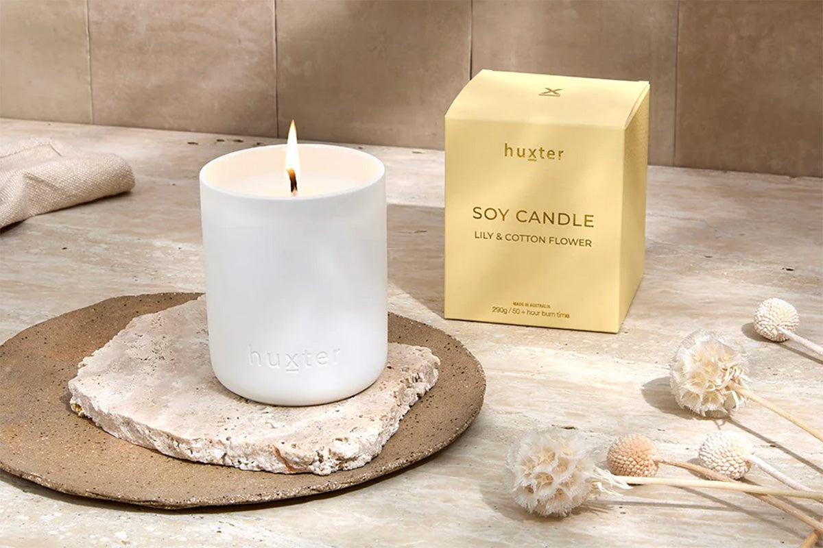White candle on a stone coaster with a gold &