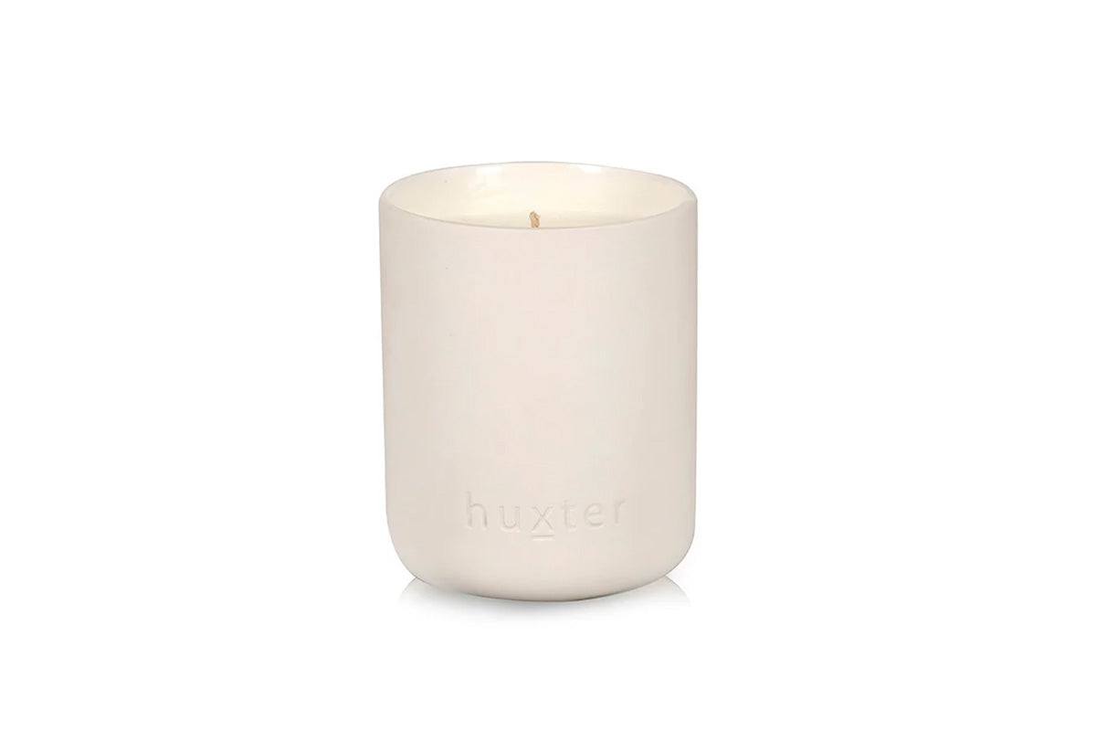 White Huxster candle in a ceramic holder on a white background