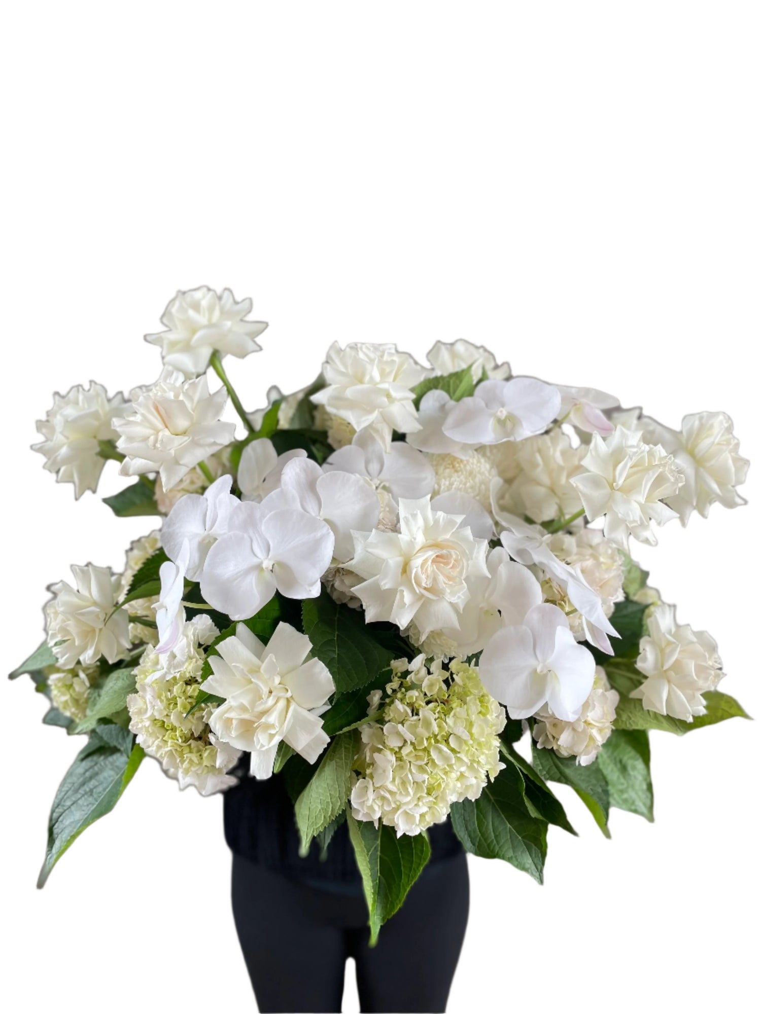 Large white and green casket tribute design, being held by a florist wearing black and standing in front of a white wall.