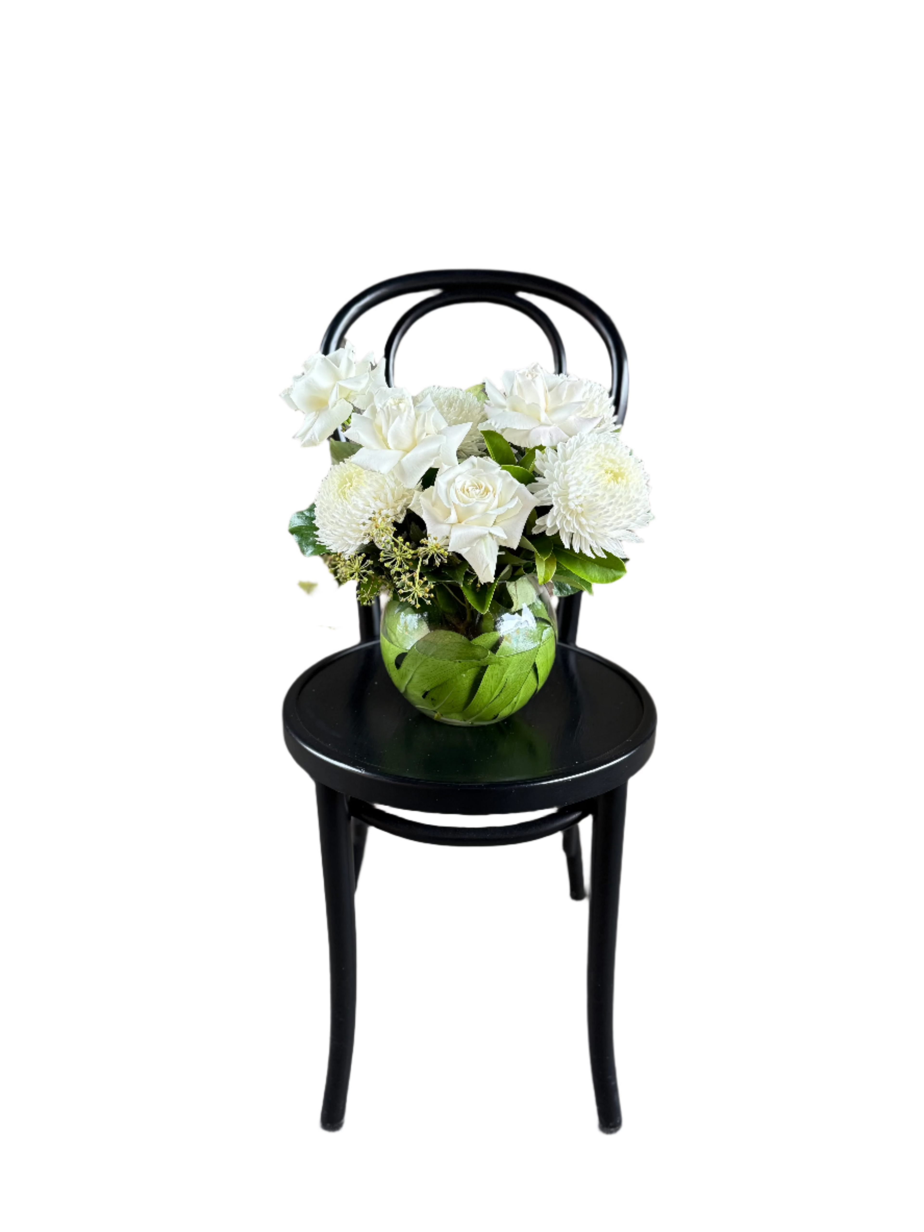 A classic white and green ball vase design sitting on a black bentwood chair.