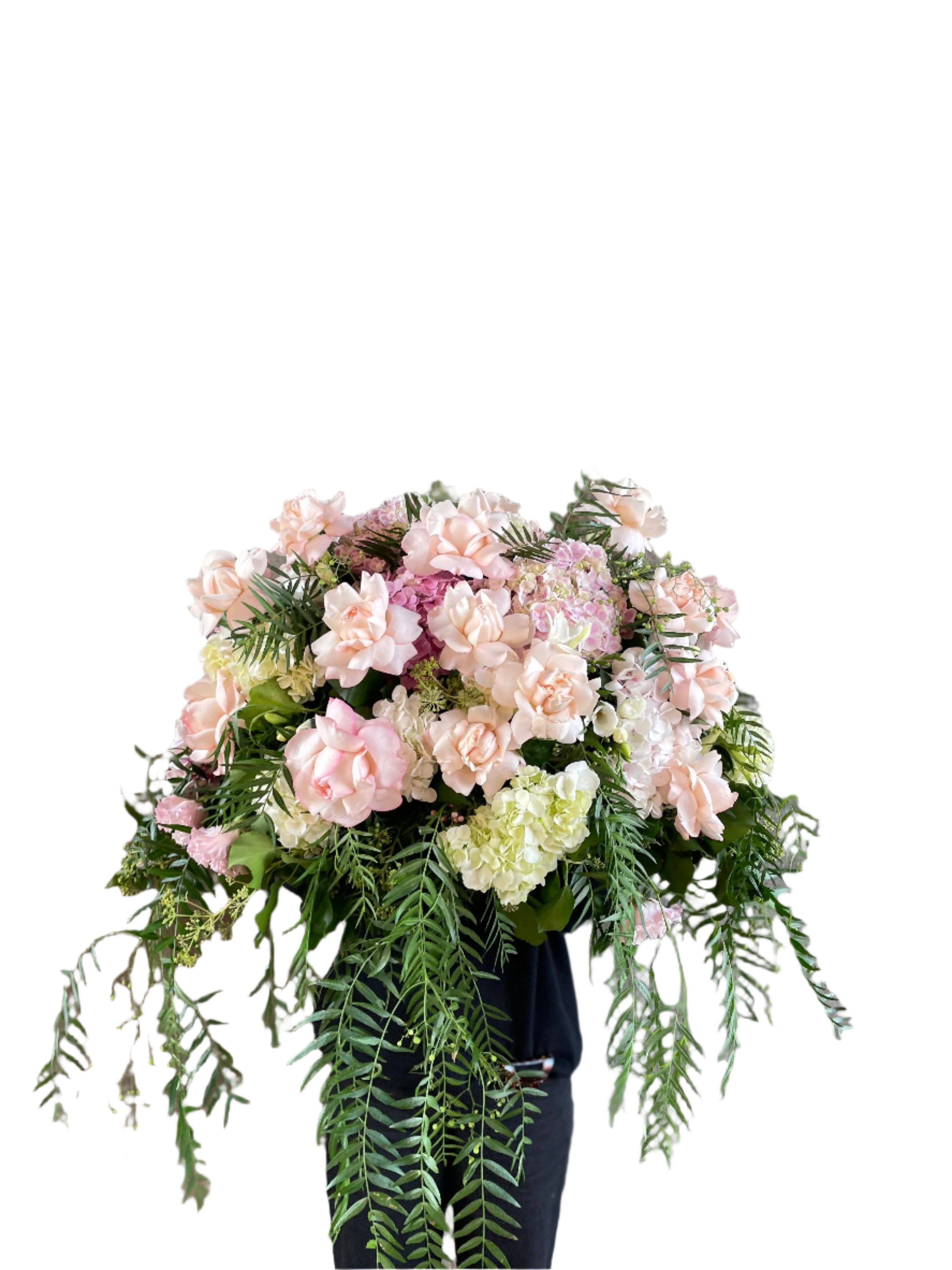 Pastel pink, white and green casket design, held by a florist wearing back, up against a funeral wall.