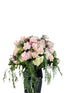 Pastel pink, white and green casket design, held by a florist wearing back, up against a funeral wall.