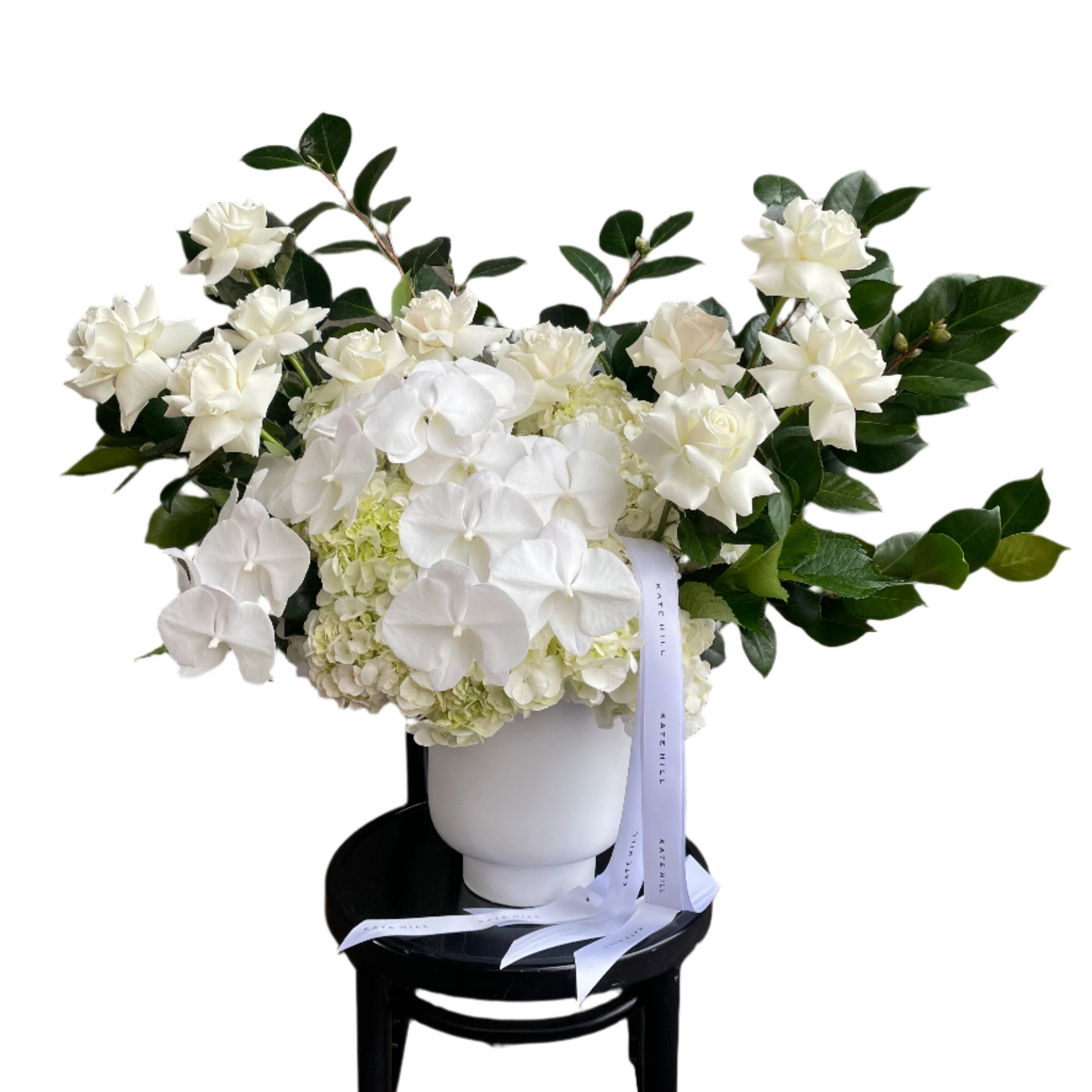 A large luxe white flower design sitting on a black bentwood chair with white wall behind.