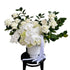 A large luxe white flower design sitting on a black bentwood chair with white wall behind.