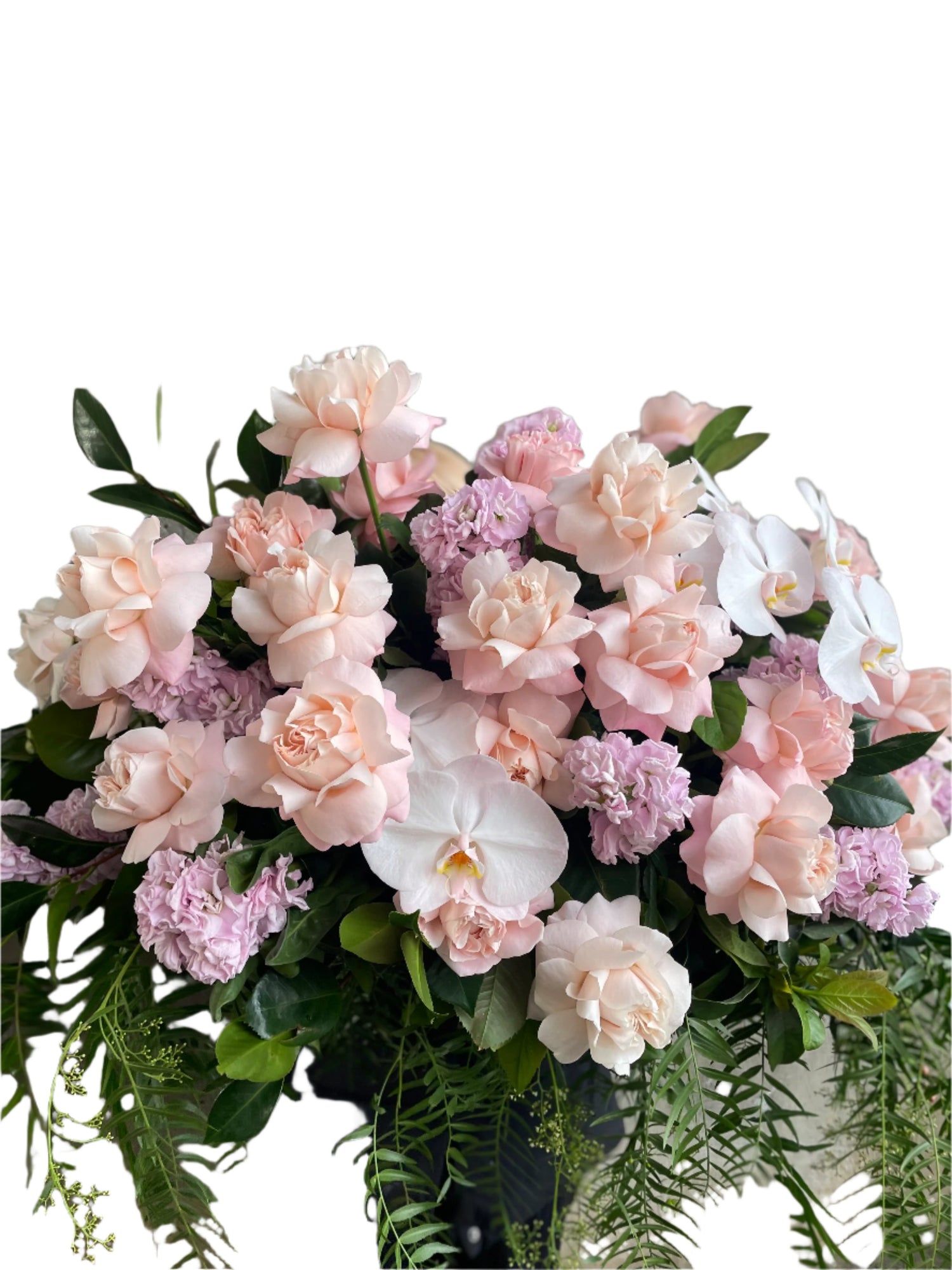 Close Pastel pink, white and green casket design, held by a florist wearing back, up against a white wall.