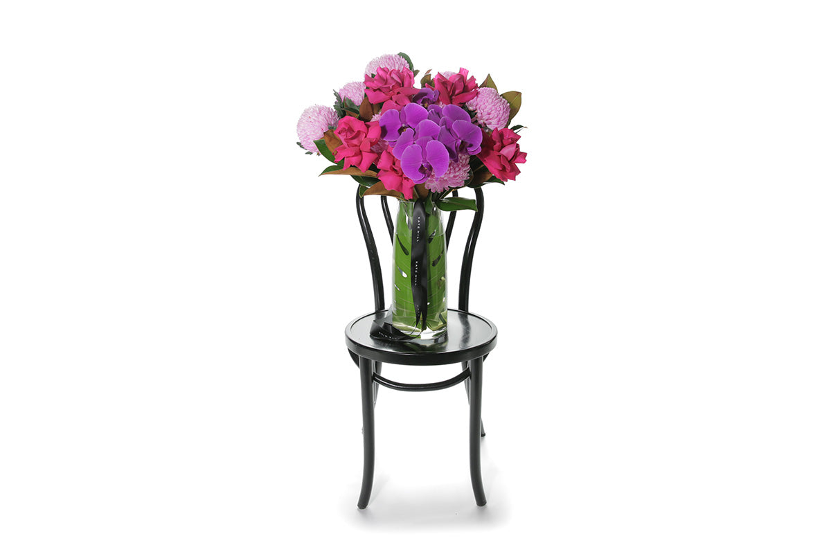 Kate Hill Flowers – large bright-pink and magenta birthday vase with roses, chrysanthemums and orchids in a monstera-lined glass.