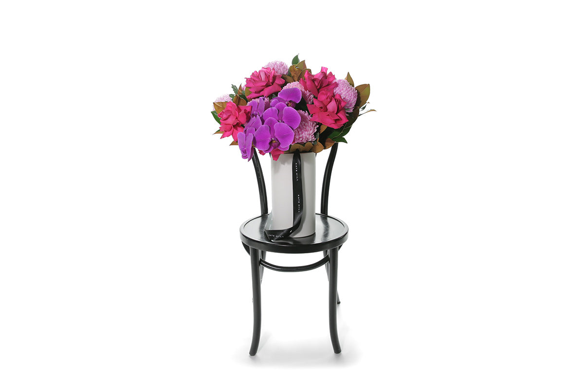 Kate Hill Flowers – large hot-pink birthday vase with roses, disbuds, orchids and magnolia in a white ceramic cylinder.