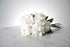 Reflexed white rose bridal bouquet with satin wrap and pearl pin finish placed on marble