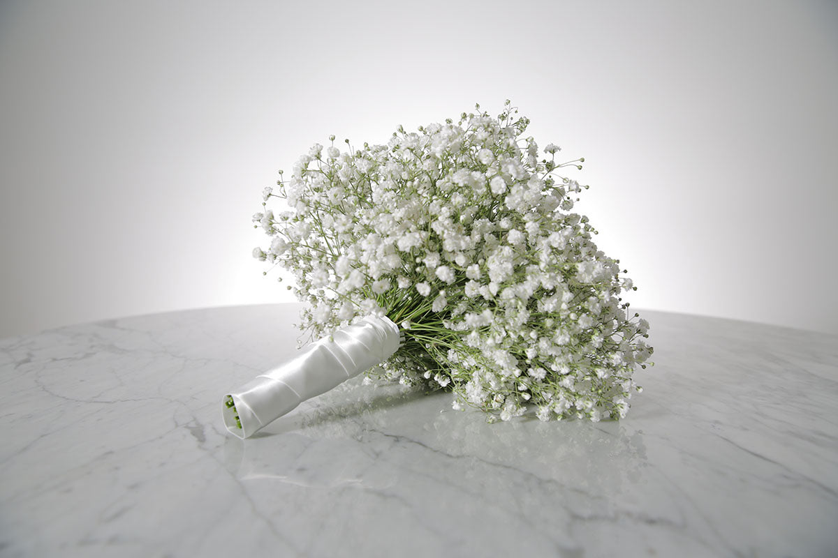 Bouquet of white Gypsophila wedding flower bouquet on a marble surface with a light grey background
