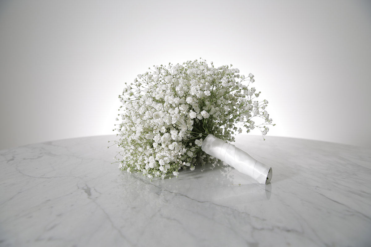 Bouquet of white Gypsophila wedding flower bouquet on a marble surface with a light grey background