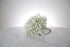 Petite white gypsophila bridesmaid bouquet with satin ribbon and pearl-pin finish placed on a marble surface