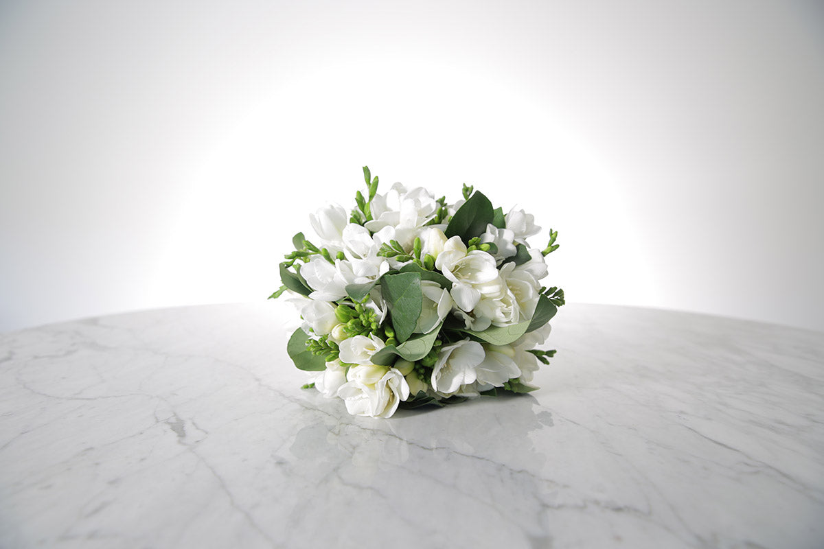 White wedding flower bouquet on a marble surface with a white background
