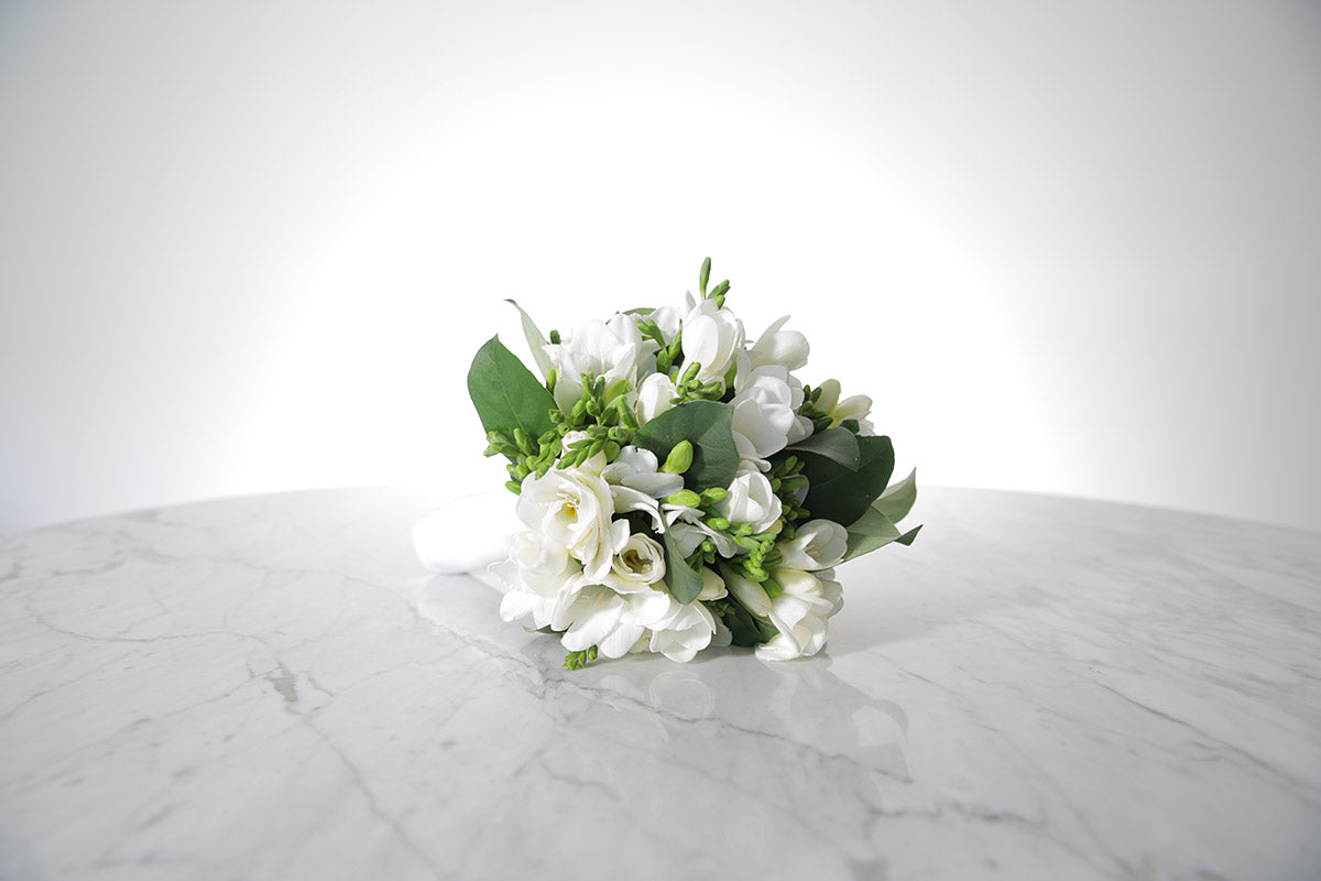 White wedding flower bouquet on a marble surface with a white background