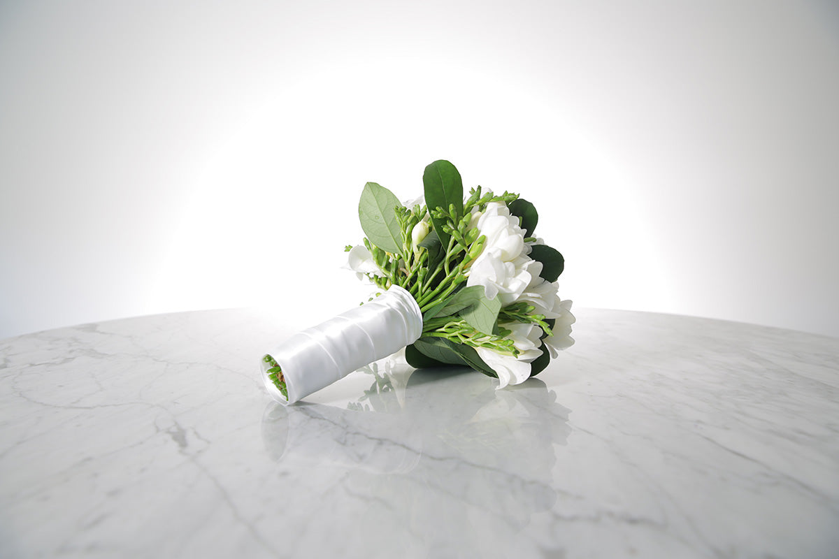 White wedding flower bouquet on a marble surface with a white background