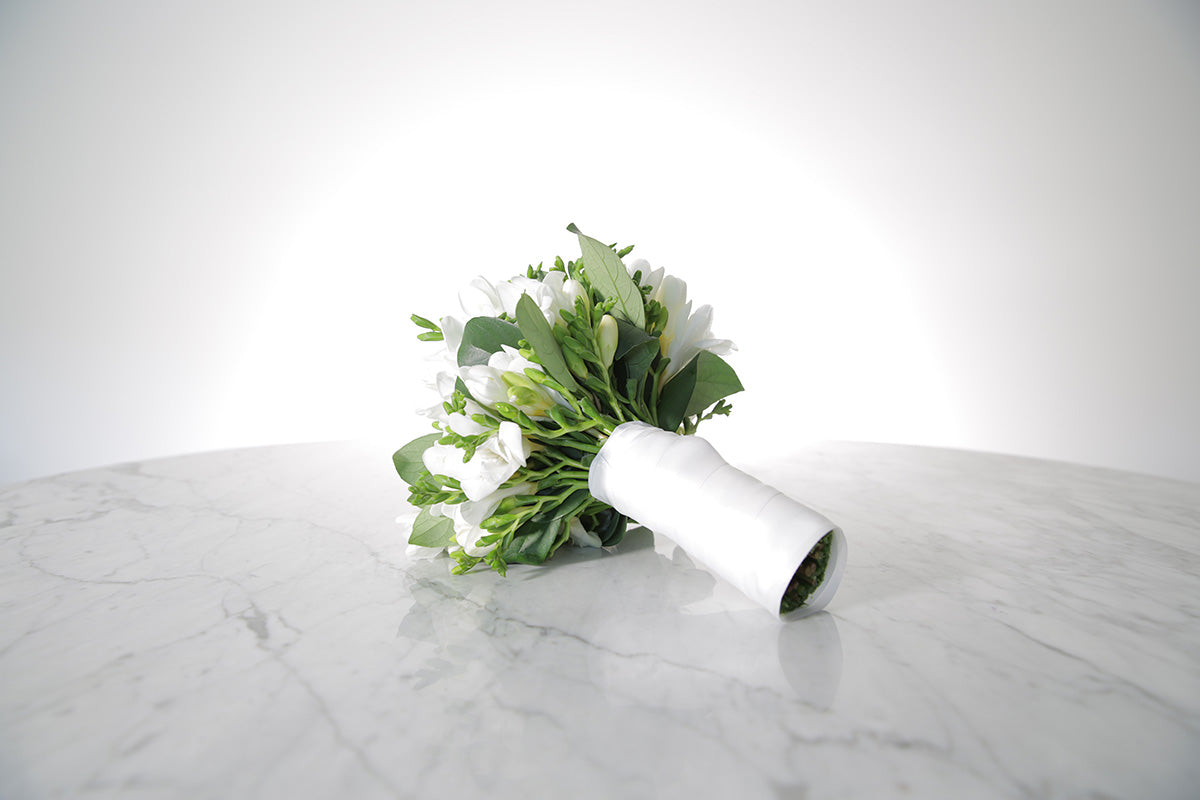 White wedding flower bouquet on a marble surface with a white background