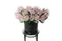 Close up image of Faux pink king protea stems displayed in a black pot, sitting on a black bentwood chair , with white background.