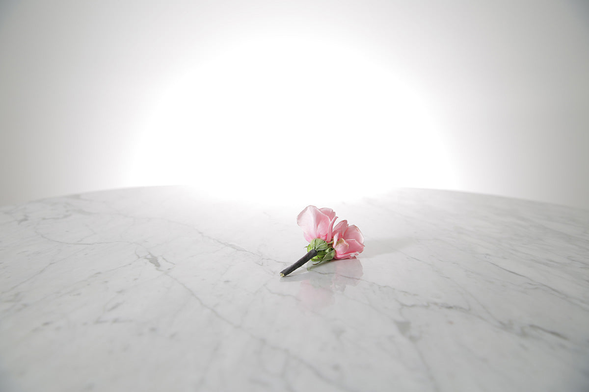 Kate Hill Flowers – pink spray rose buttonhole flowers with black-taped stem and pearl pin on a marble table setting.