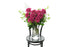 Hot pink reflexed roses displayed in a clear glass tapered vase sitting on a black bentwood chair with white background.