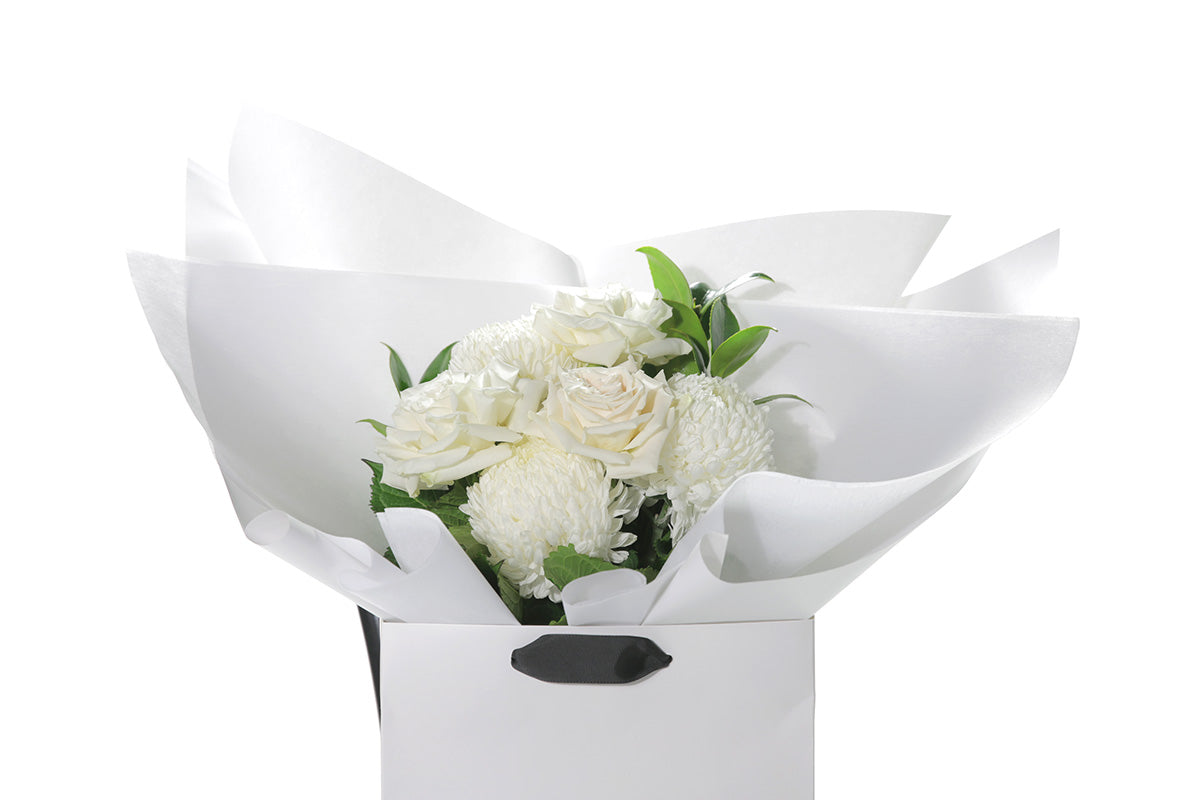 Kate Hill Flowers – small white sympathy posy of roses and chrysanthemums in a water-filled gift bag.