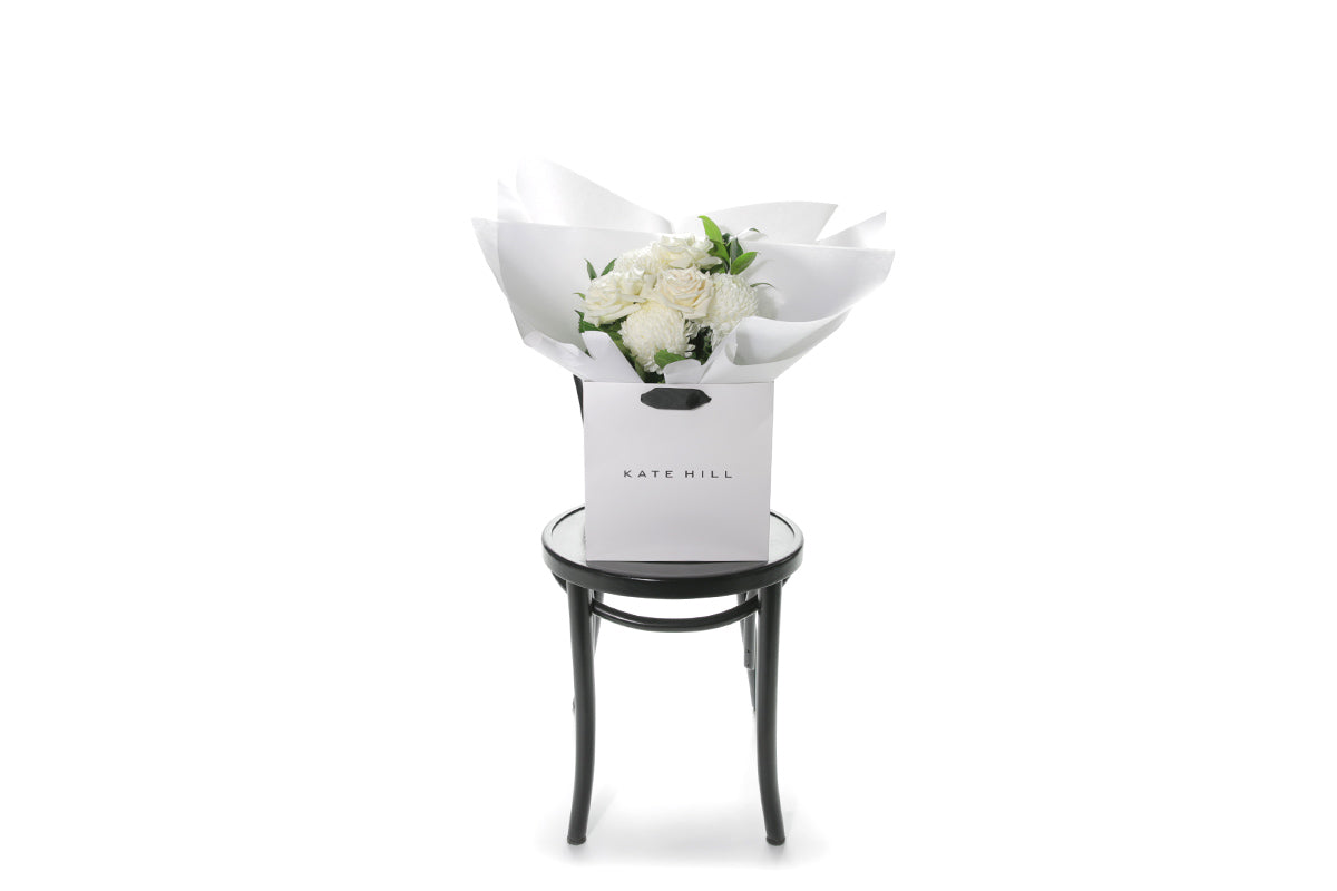 Kate Hill Flowers – small white sympathy posy of roses and chrysanthemums in a water-filled gift bag.