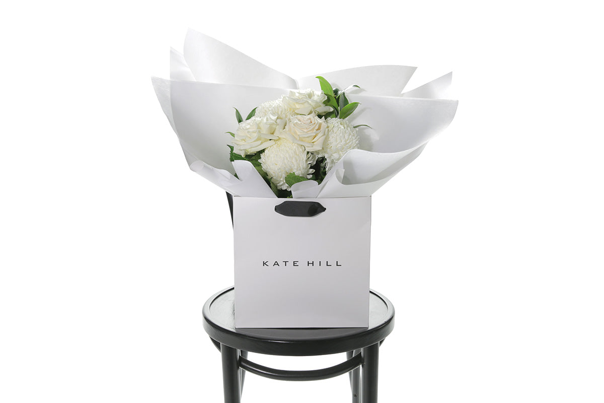 Kate Hill Flowers – small white sympathy posy of roses and chrysanthemums in a water-filled gift bag.