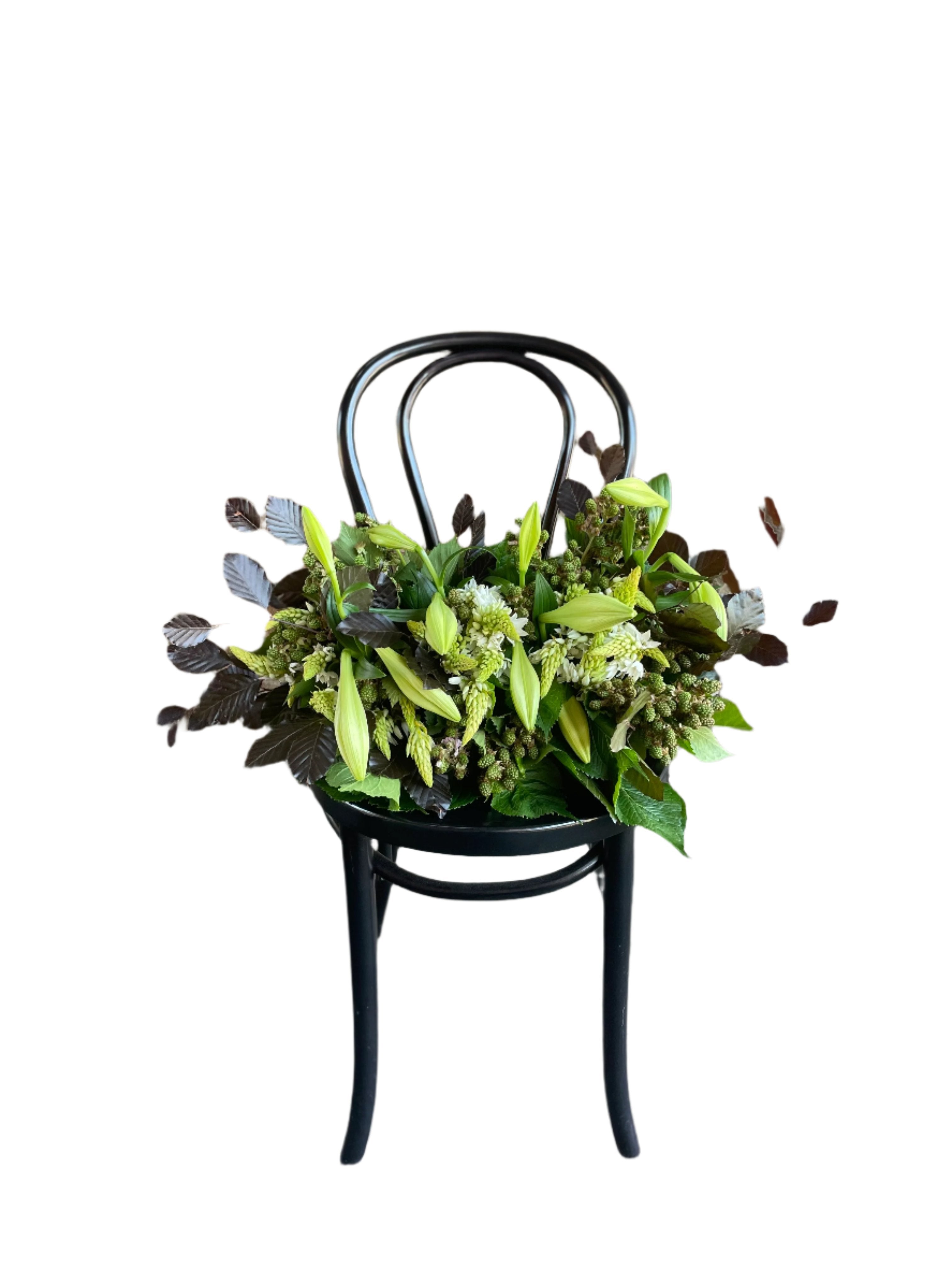 A Christmas Table Design sitting on a black bentwood chair with a white wall background.