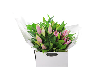 Close up image of the VARDA pink lily bouquet. VARDA Lily Flower Bouquet features a simple bouquet of pink oriental Lilies and green seasonal foliage.