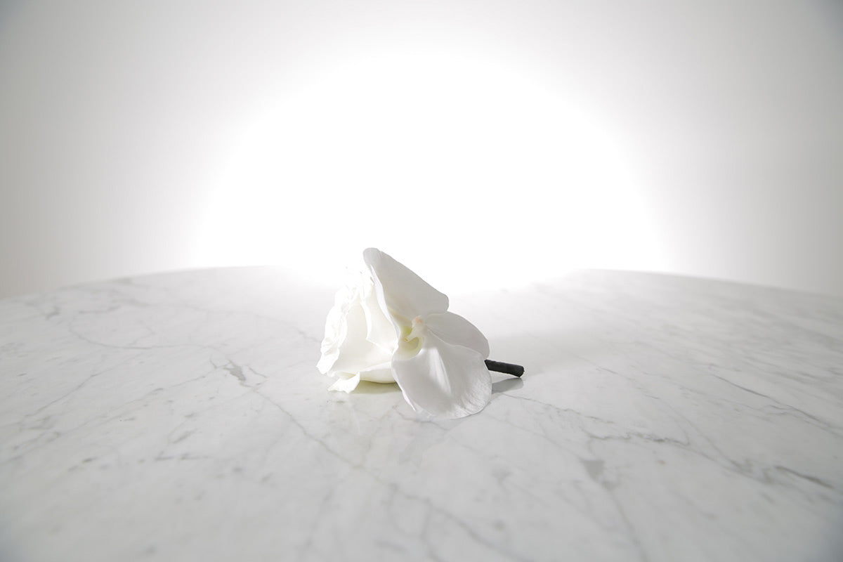 White buttonhole on a marble surface with a light grey background