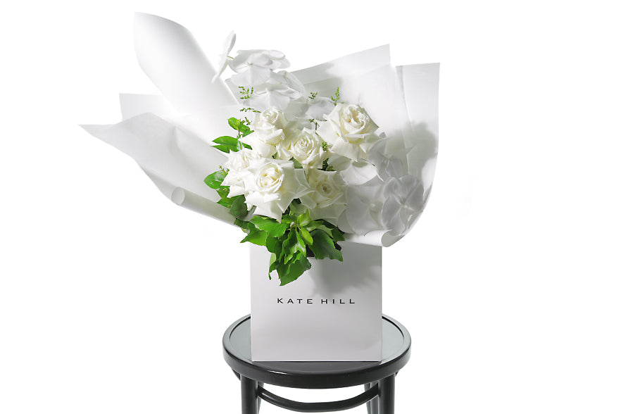 White rose bouquet featuring white phalaenopsis orchids in Kate Hill gift bag