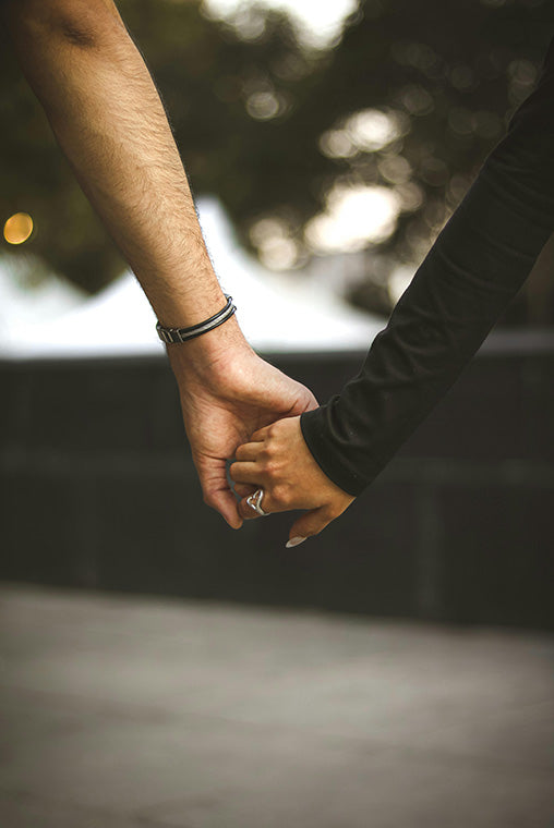 Two people holding hands with a blurred background