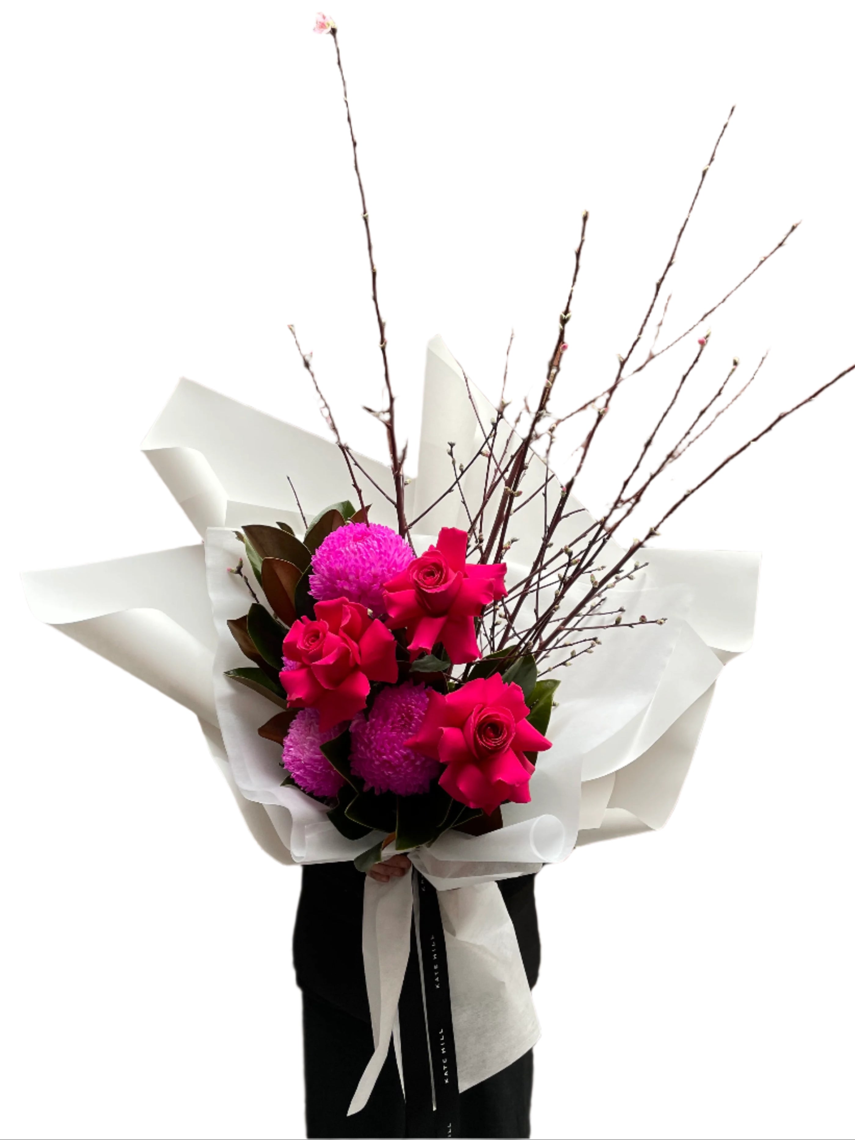 A Melbourne florist wearing black holding a bouquet of flowers with hot pink flowers wrapped in white paper against a white wall.