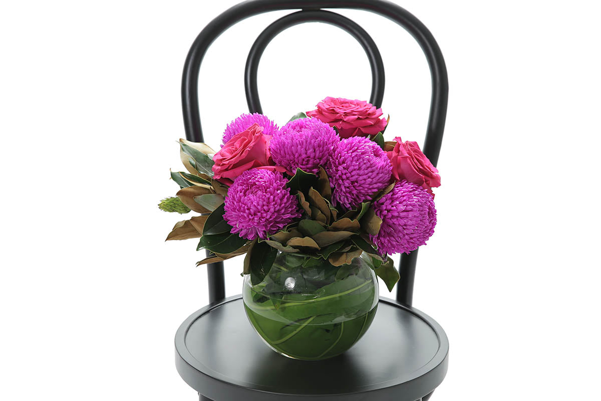 Close-up of MAYA ball vase with hot pink disbuds and roses