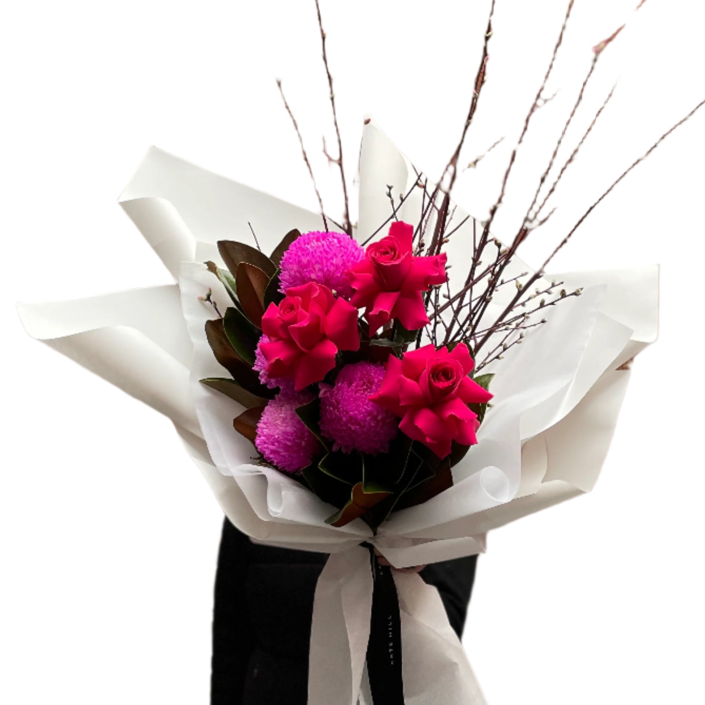 A Melbourne florist wearing black holding a bouquet of flowers with hot pink flowers wrapped in white paper against a white wall.