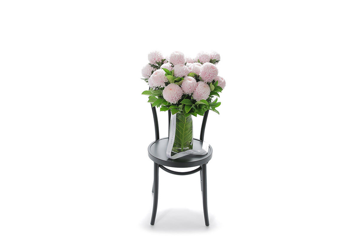 VIVIENNE soft pink disbuds in a tapered glass vase lined with monsteria