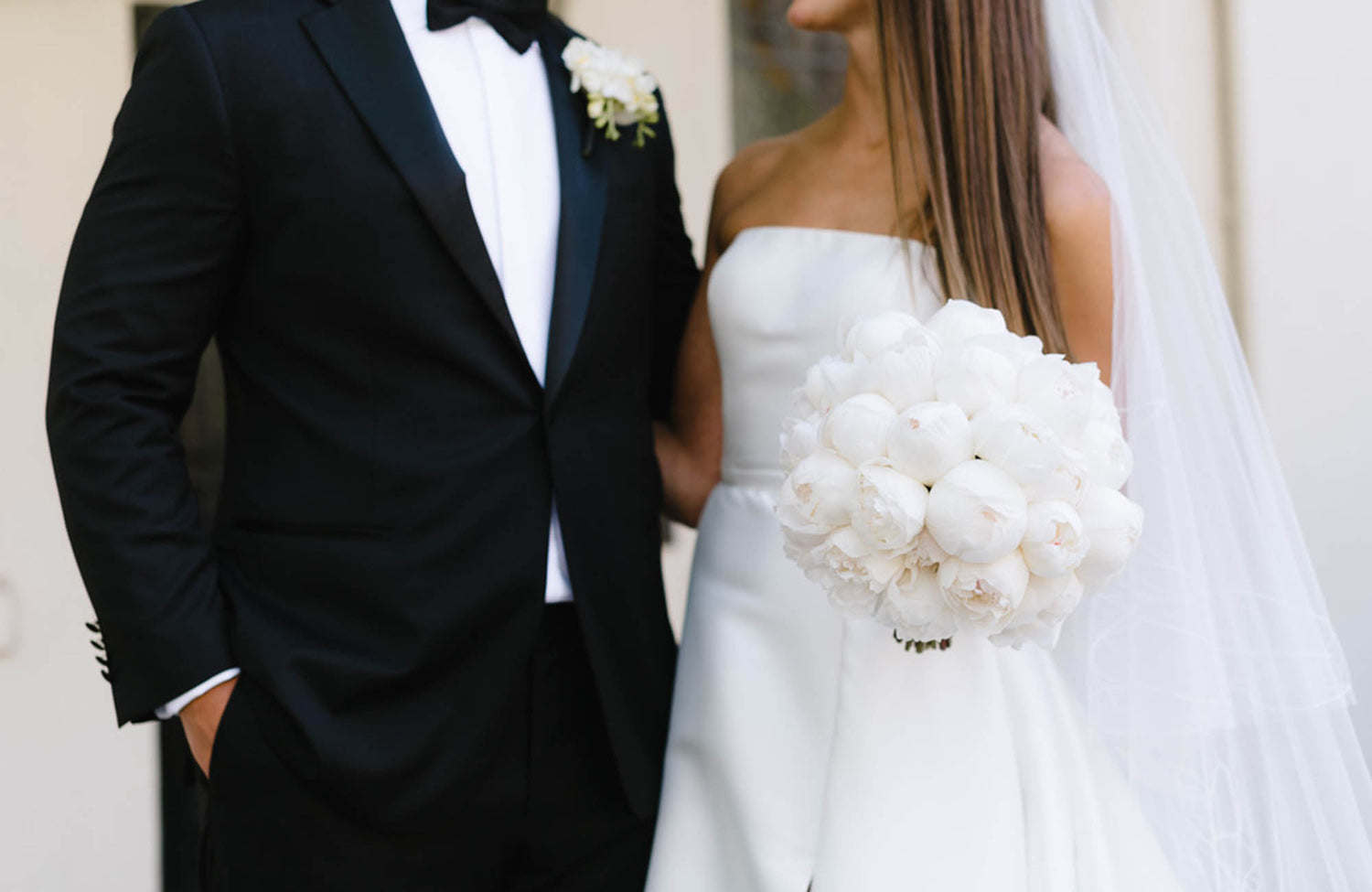 Bride and groom with bride's white bridal bouquet being held