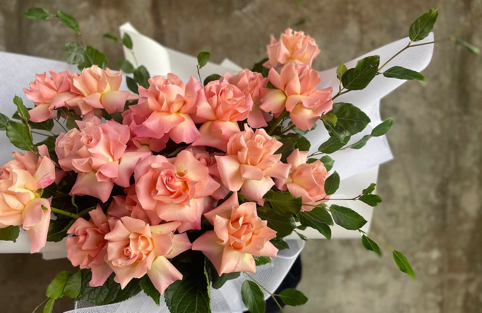 Bouquet of roses in orange hues, in white wrapping 