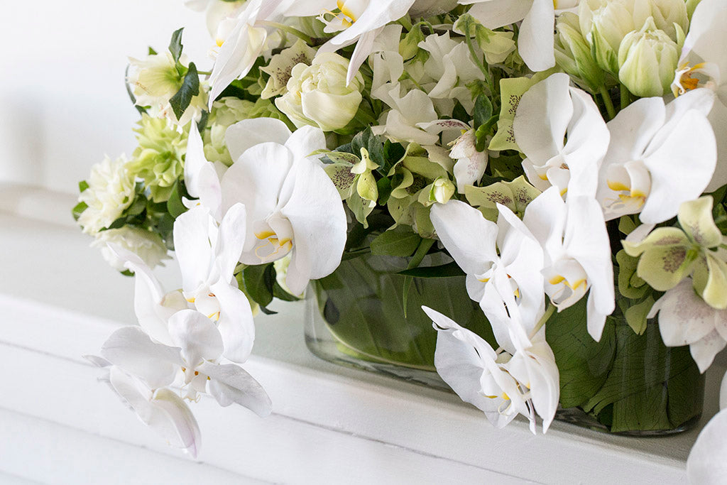 White arrangement of flowers in vase on shelf