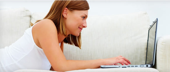 Woman laying on stomach on couch with computer open researching wedding flowers