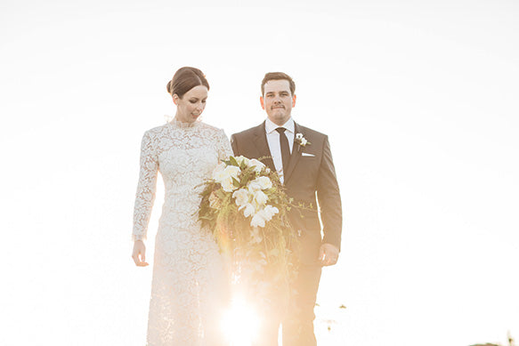 Newly wedded bride holds her wedding bouquet with husband