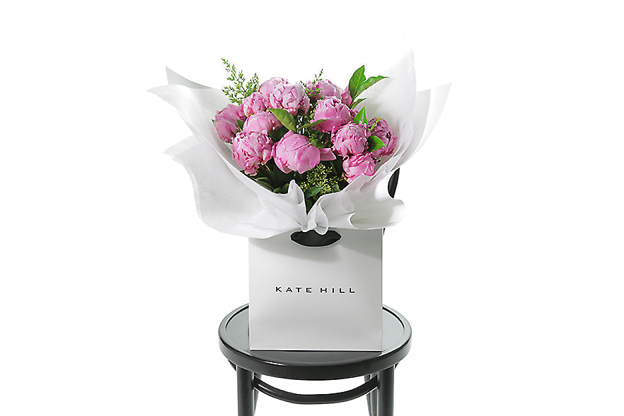 Pink Penny flower bouquet by Kate Hill Flowers on a Blackwood chair with a white background